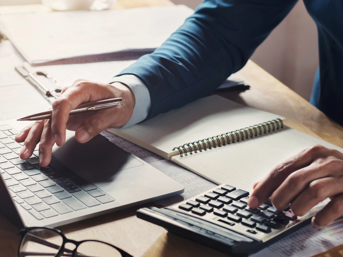 Business professional working with calculator and laptop