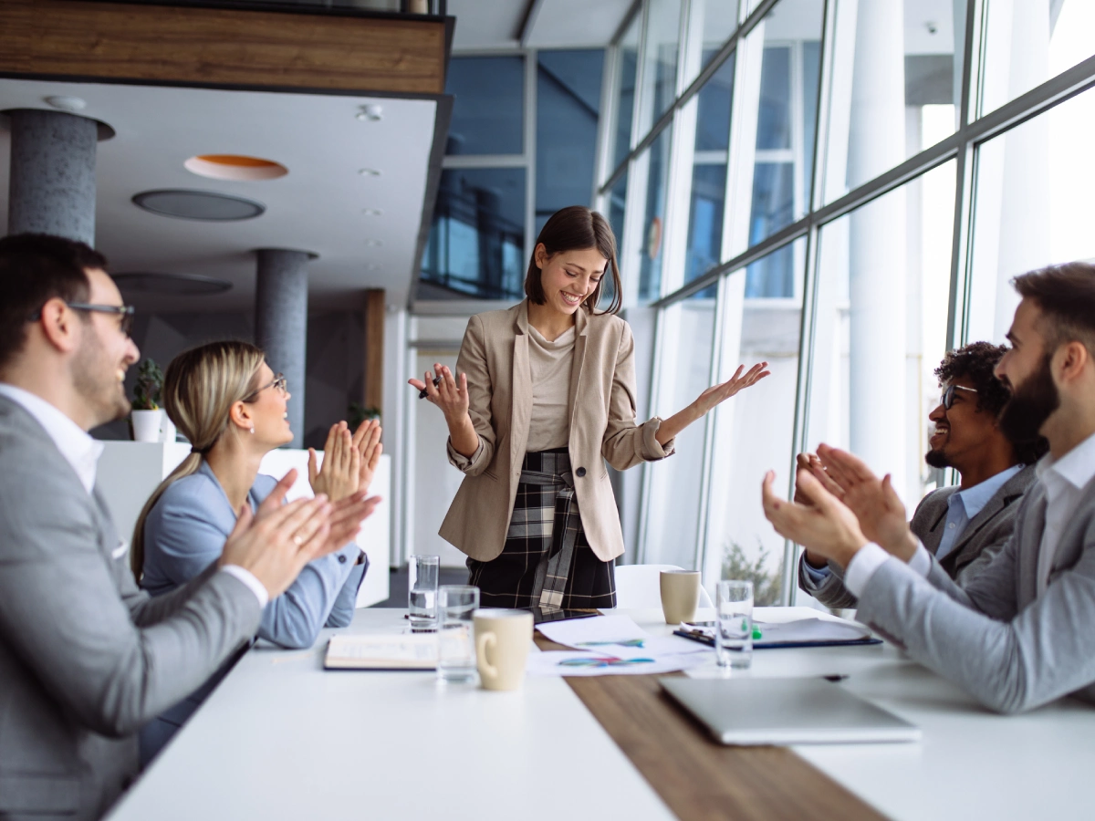 Businesswoman presenting to applauding colleagues