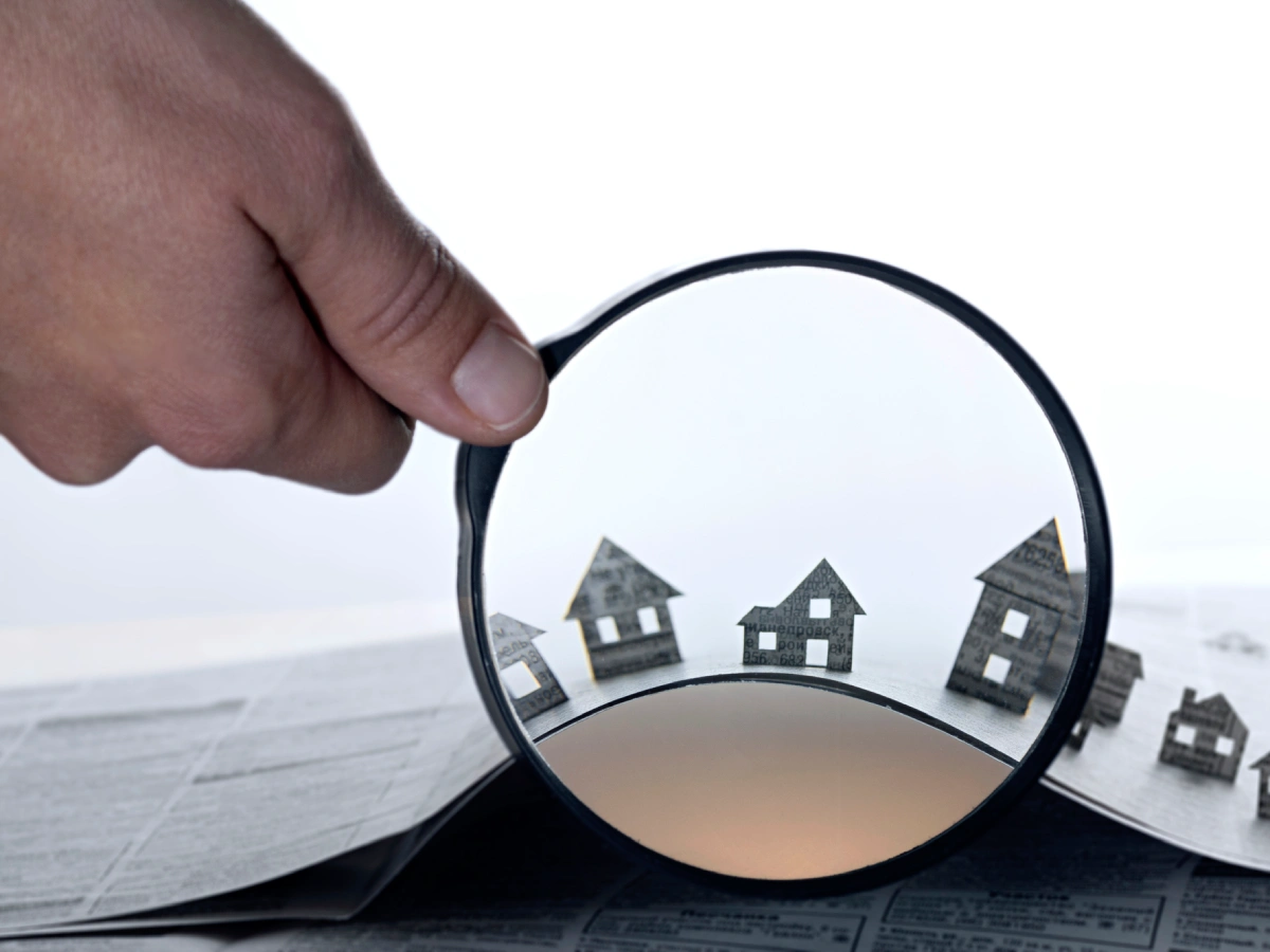 Magnifying glass over small paper houses