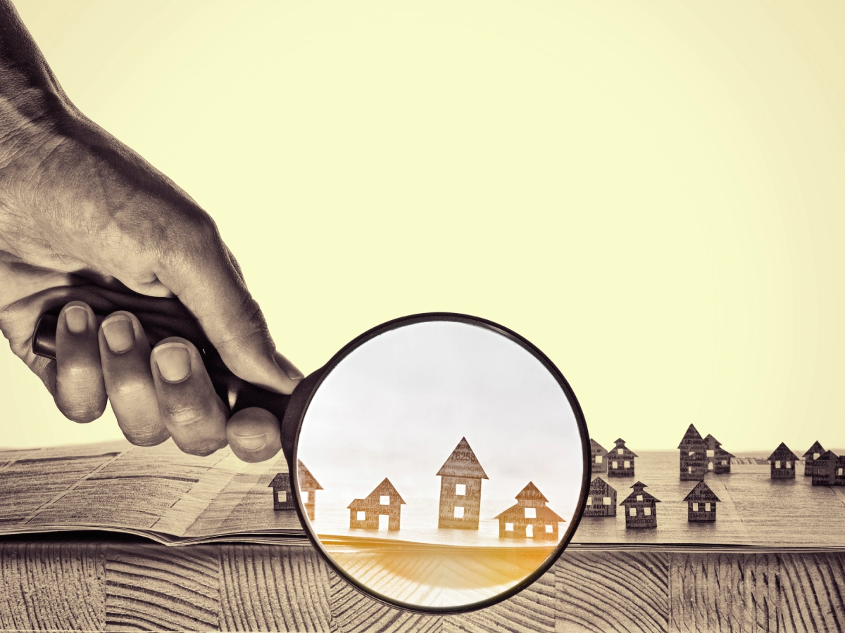 Hand holding magnifying glass on houses